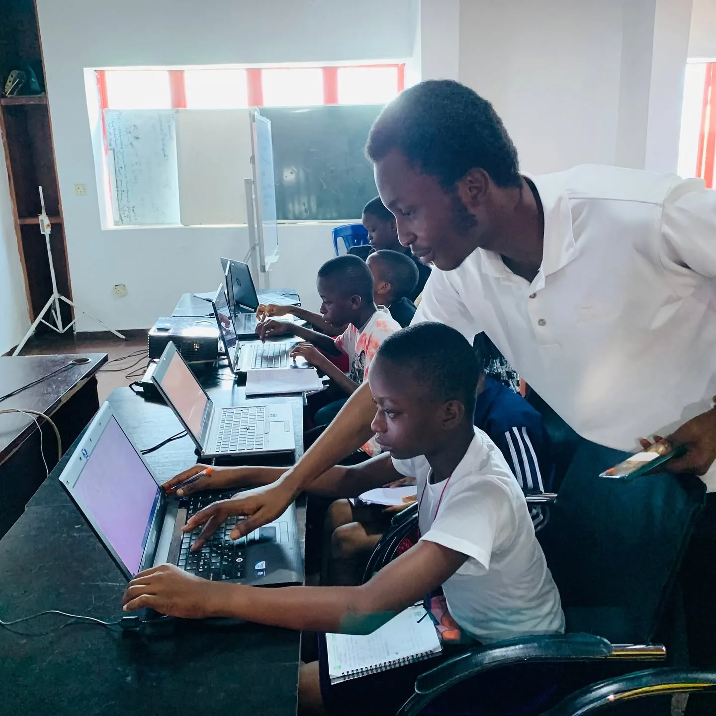 A MejorTech instructor guiding a learner at a laptop during a coding class